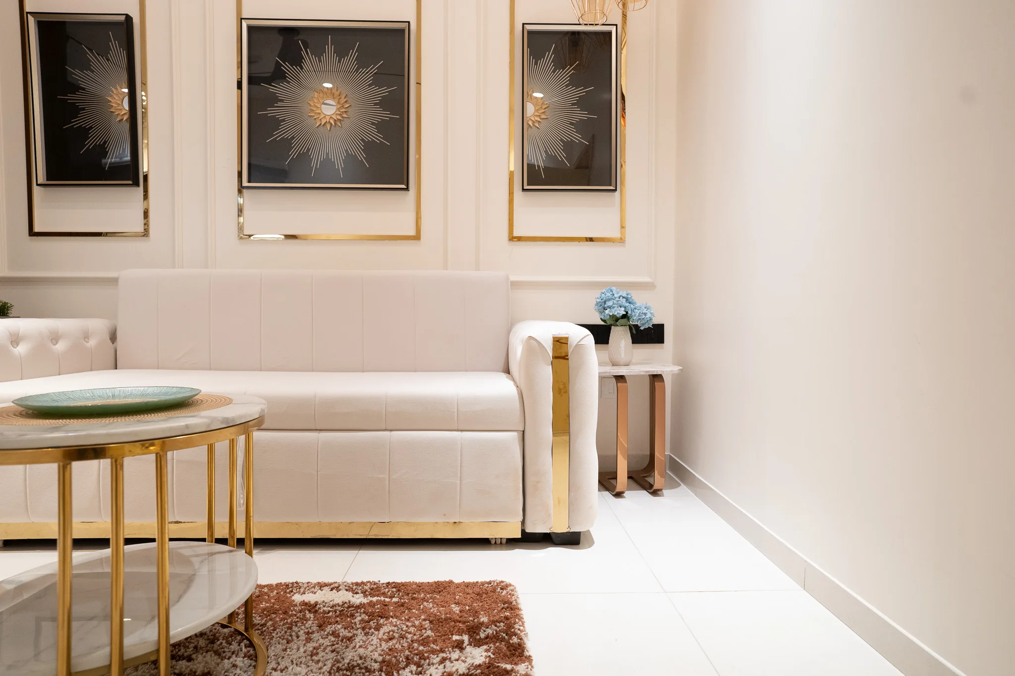 Cream tufted sofa beneath framed starburst artwork, with gold accents