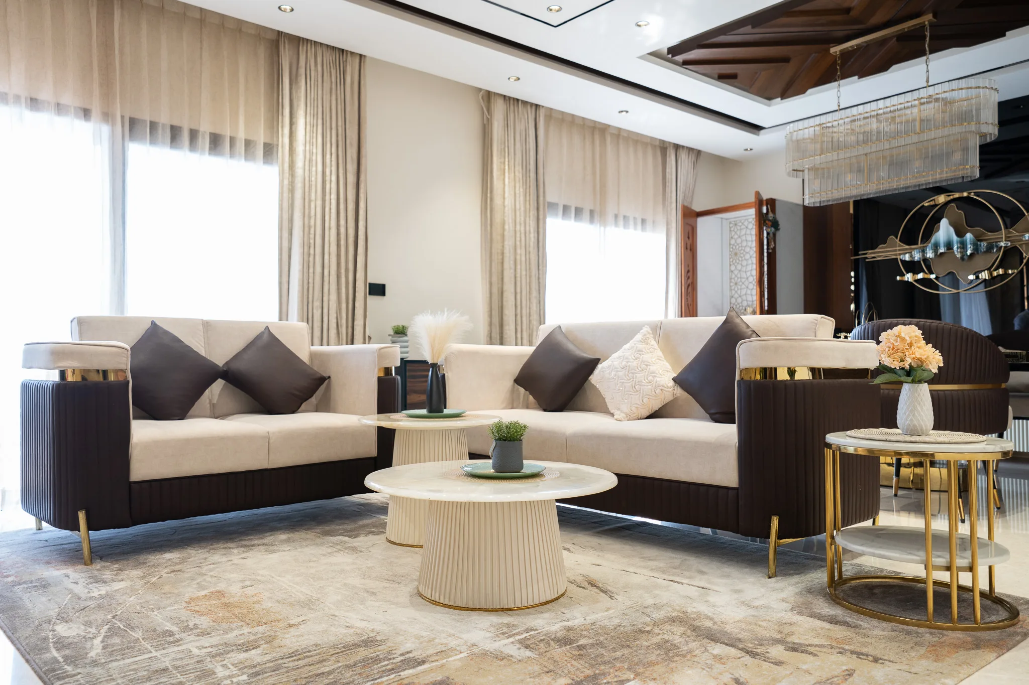 Living room with cream and charcoal sofas, gold side tables and crystal chandelier